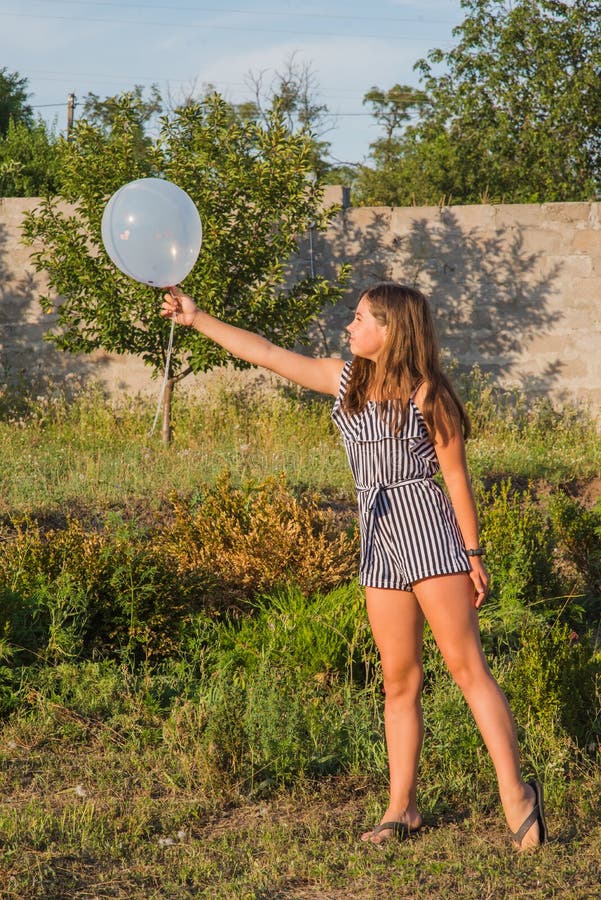 Outdoors portrait of beautiful young brunette girl. Teenager girl and balloons. Girl, balloons, holiday, birthday