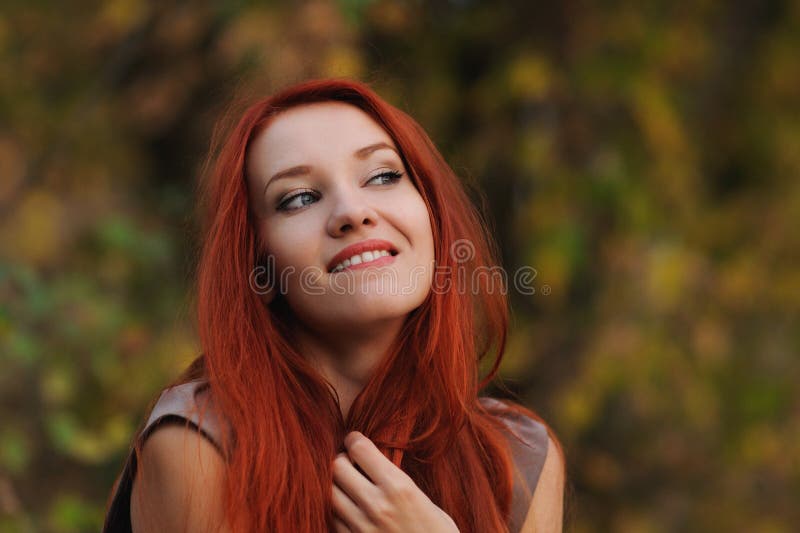 Outdoors portrait of beautiful young woman with red hair