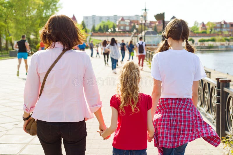 Outdoors portrait of mother and two daughters. Holding hands walking down the street, back view royalty free stock photography Outdoors portrait of mother and two daughters. Holding hands walking down the street, back view royalty free stock photography