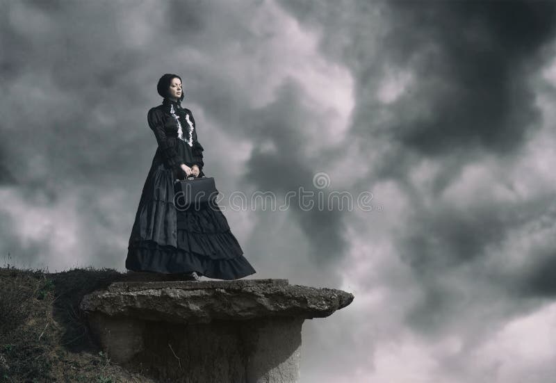 Outdoors portrait of a victorian lady in black standing on the cliff