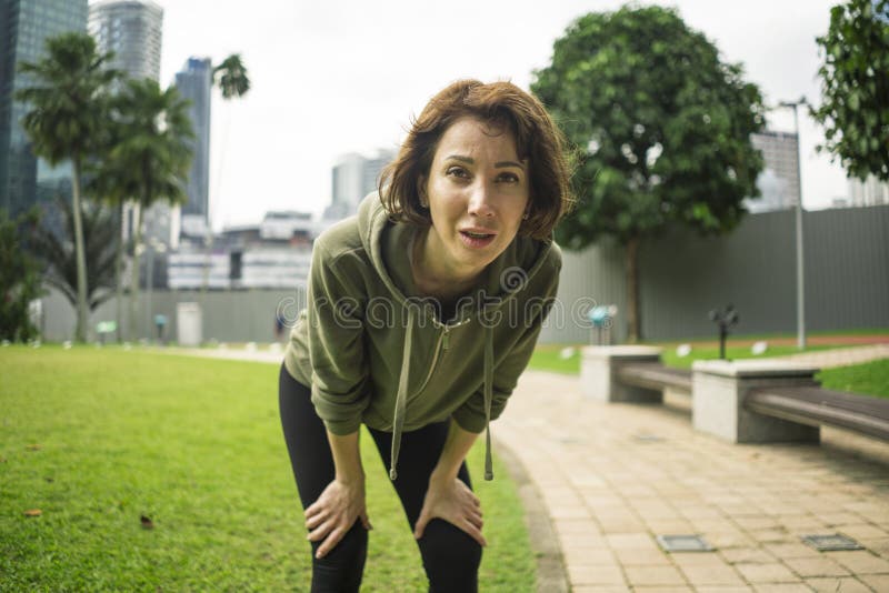 Outdoors portrait of young attractive tired and breathless jogger woman in breathing exhausted after running workout at beautiful stock images Outdoors portrait of young attractive tired and breathless jogger woman in breathing exhausted after running workout at beautiful stock images