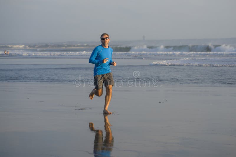 Outdoors running workout - young attractive and athletic runner man jogging on beautiful beach in Summer training happy and free stock images Outdoors running workout - young attractive and athletic runner man jogging on beautiful beach in Summer training happy and free stock images