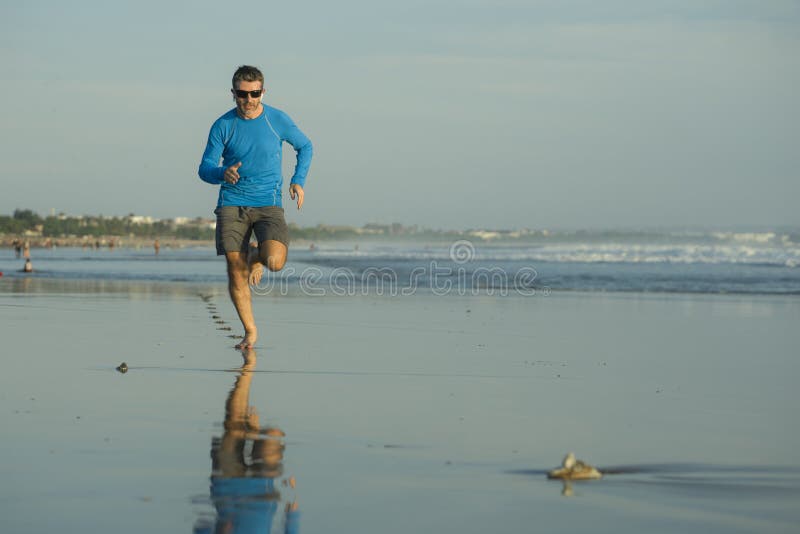 Outdoors running workout - young attractive and athletic runner man jogging on beautiful beach in Summer training happy and free stock images Outdoors running workout - young attractive and athletic runner man jogging on beautiful beach in Summer training happy and free stock images