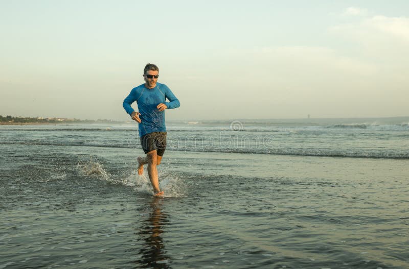 Outdoors running workout - young attractive and athletic runner man jogging on beautiful beach in Summer training happy and free royalty free stock photos Outdoors running workout - young attractive and athletic runner man jogging on beautiful beach in Summer training happy and free royalty free stock photos