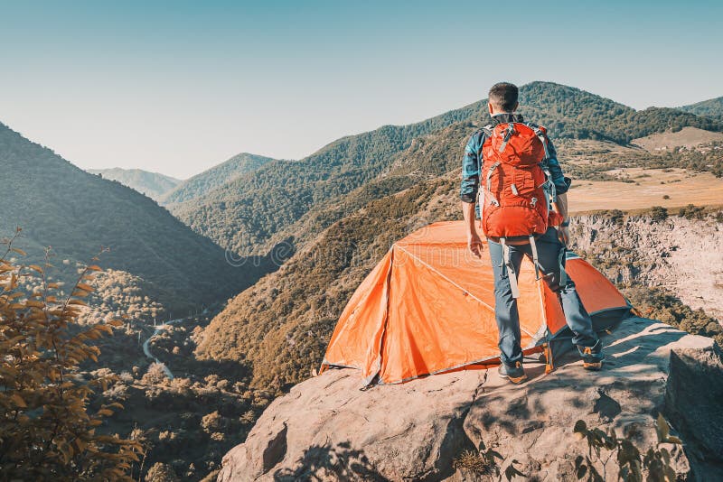 Outdoorsman traveler with backpack stands on cliff with his tent with a gorgeous view of a mountain valley in Armenia. Camping royalty free stock photos
