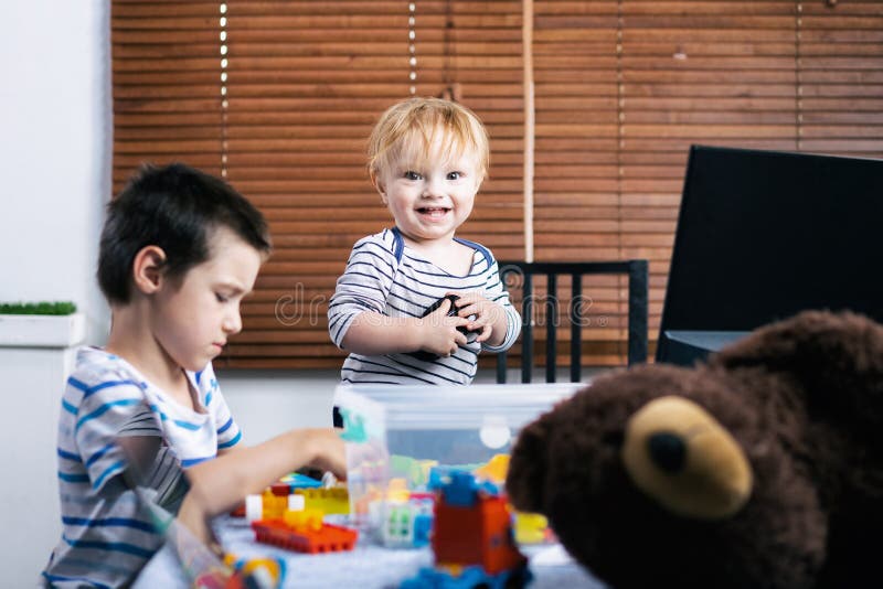 Ouverture de la maison avec des enfants en bas âge. Deux petits garçons s'amusent jouant le constructeur multicolore de plastique à la table. Amitié et match entre les frères à la maison
