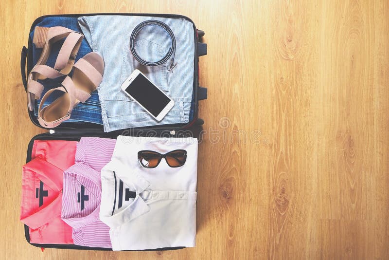 Ouvrez la valise avec les vêtements et les accessoires femelles à la mode sur la vue supérieure de plancher en bois, l'espace de photo libre de droits Ouvrez la valise avec les vêtements et les accessoires femelles à la mode sur la vue supérieure de plancher en bois, l'espace de photo libre de droits