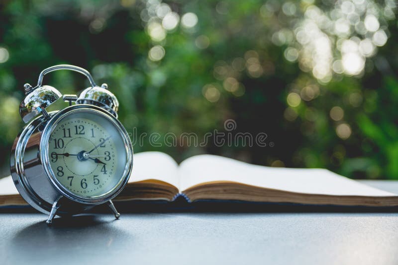 Ouvrez le livre avec le réveil Livre ouvert sur la vieille table en bois sur national photos stock Ouvrez le livre avec le réveil Livre ouvert sur la vieille table en bois sur national photos stock