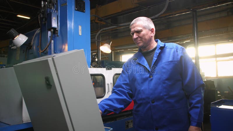 Ouvrier aux cheveux gris au panneau de commande de la machine dans l'atelier clips vidéos
