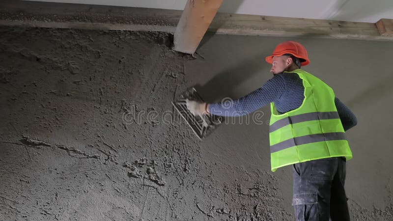 Ouvrier de construction qui applique le plâtre à un mur Un ouvrier de construction dans un chapeau dur et un gilet de sécurité qui banque de vidéos