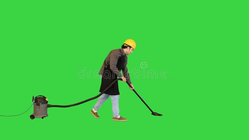 Ouvrier de construction travaillant sur le site avec un aspirateur et souriant sur caméra sur un écran vert clé chroma. clips vidéos