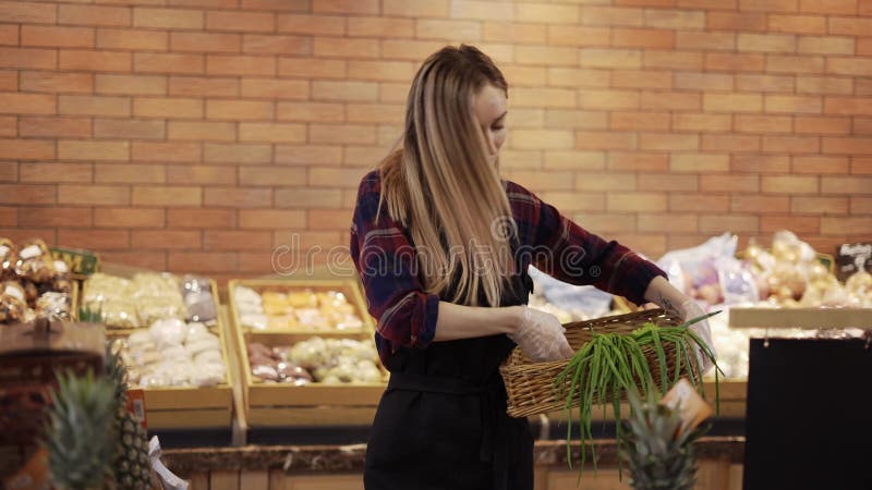 Ouvrier souriant en tablier noir arrangeant des verts dans un supermarché banque de vidéos