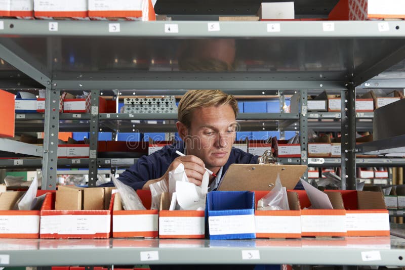 Male Factory Worker In Store Room Checking Stock. Male Factory Worker In Store Room Checking Stock