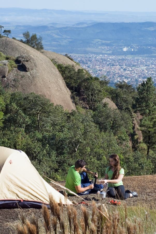 Young, attractive couple camping out on a gorgeous summer day with the buildings of the city visible in the background. Young, attractive couple camping out on a gorgeous summer day with the buildings of the city visible in the background