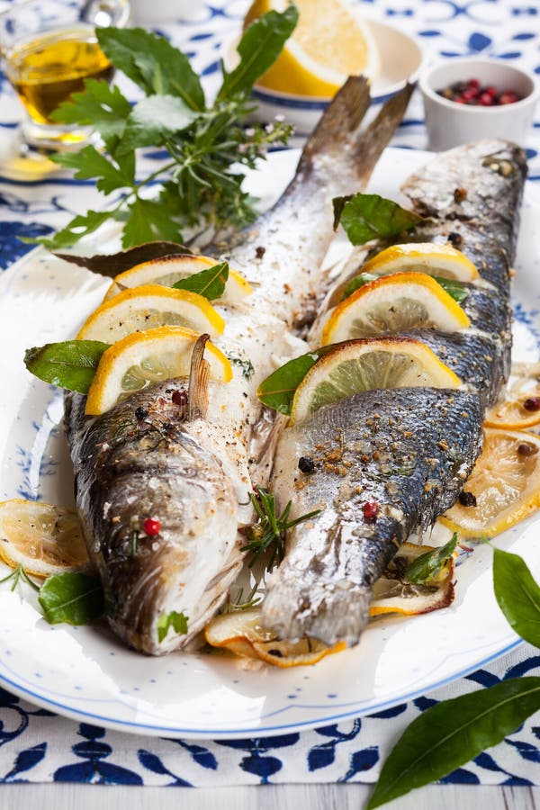 Baked Sea Bass with Tomato Pepper Lemon and Herbs on Wooden Board for