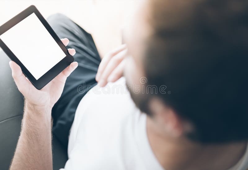 Over the shoulder view of man sitting on armchair using e-book reader or tablet computer stock photo Over the shoulder view of man sitting on armchair using e-book reader or tablet computer stock photo
