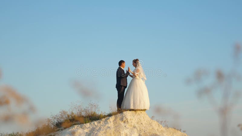 Overdrijft de mens en bruidzoen op een witte berg tegen een blauwe hemel jonge familie reist op huwelijksreis bruid en
