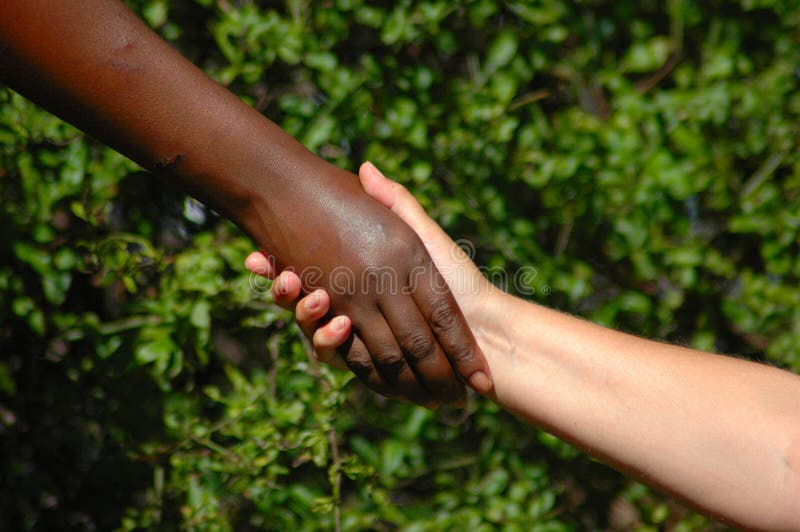 Handshake between a black hand of an African American woman and a white hand of an caucasian woman holding each other to show there agreement. Handshake between a black hand of an African American woman and a white hand of an caucasian woman holding each other to show there agreement