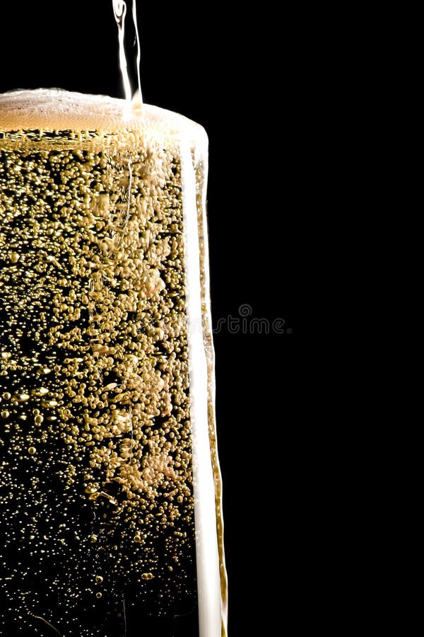 Overflow pouring champagne in the flute with golden bubbles stock photos