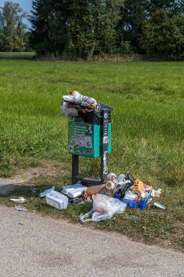 Overflowing trash can in a park stock photos