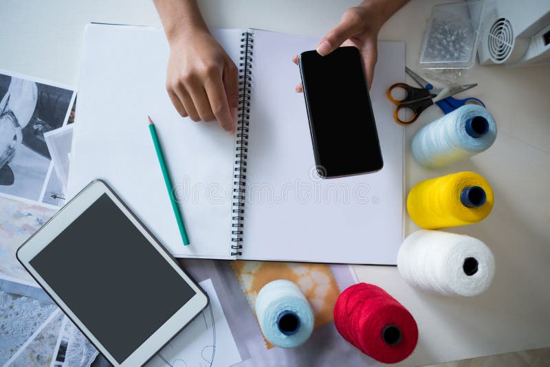 Fashion designer using mobile phone at desk royalty free stock photo Fashion designer using mobile phone at desk royalty free stock photo