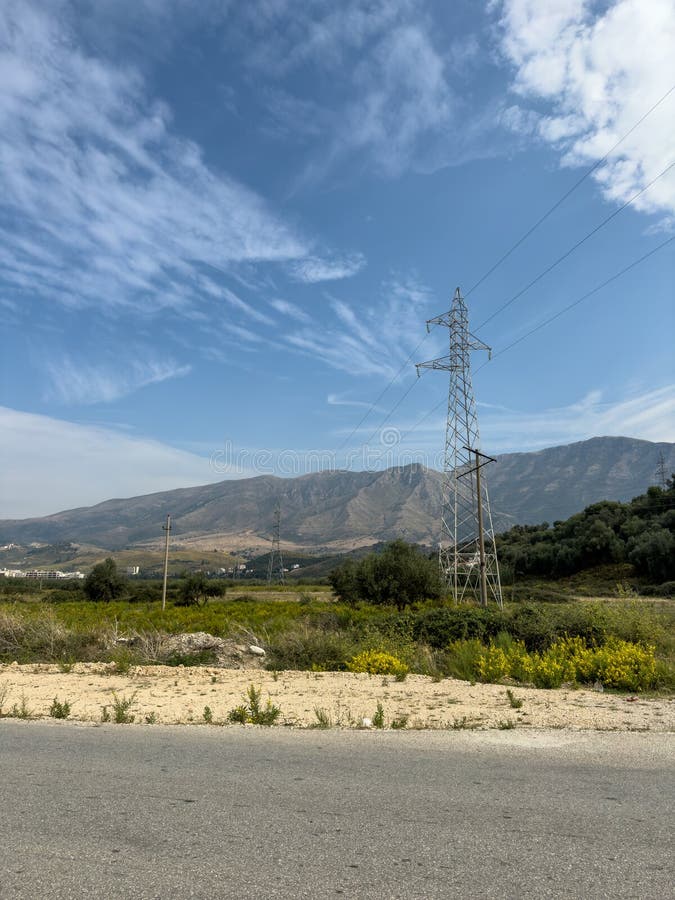 Overhead line pylons, high voltage pylons in meadow with mountains on background stock photos