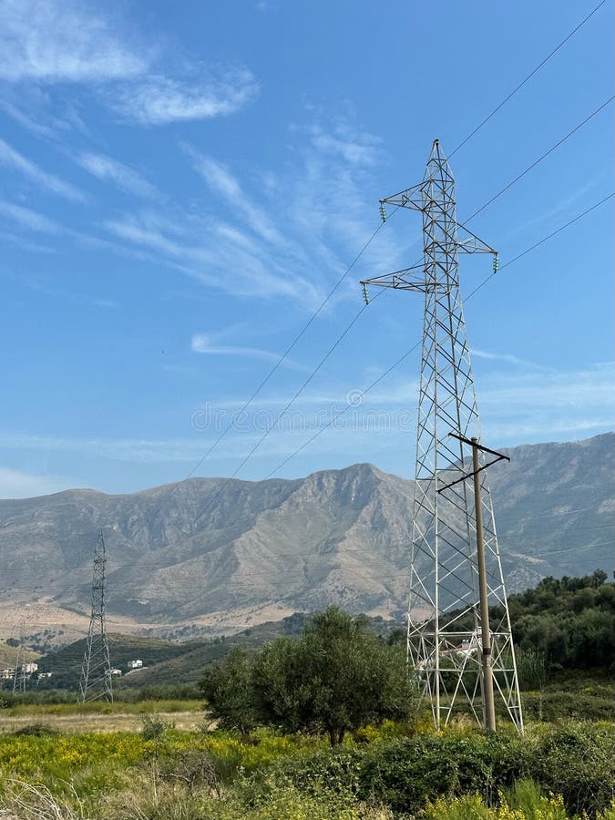 Overhead line pylons, high voltage pylons in meadow with mountains on background royalty free stock photo