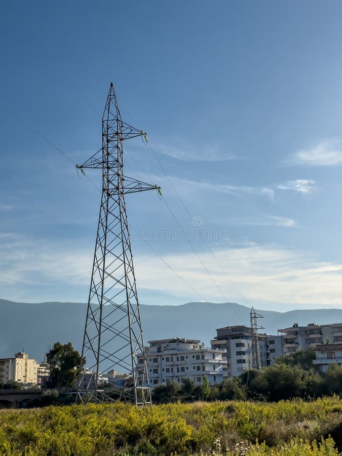 Overhead line pylons, high voltage pylons in meadow with mountains on background royalty free stock photos