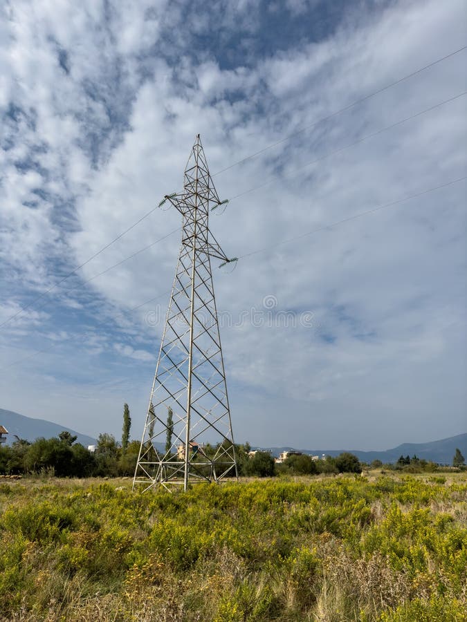 Overhead line pylons, high voltage pylons in meadow with mountains on background royalty free stock photo