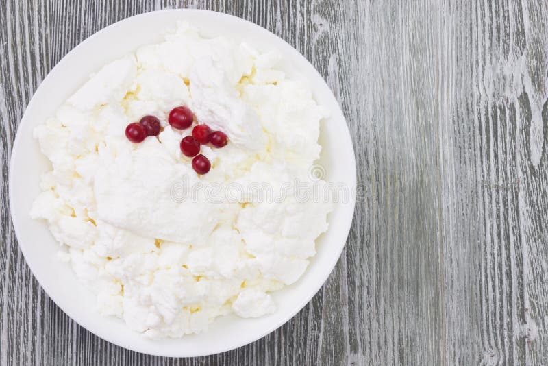 An overhead photo of fresh natural cottage cheese with cranberry yogurt in a white ceramic bowl on the wooden table. Organic eco stock image An overhead photo of fresh natural cottage cheese with cranberry yogurt in a white ceramic bowl on the wooden table. Organic eco stock image