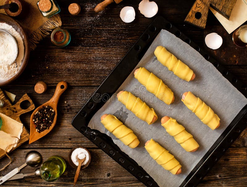 Overhead shot of delicious homemade no baked sausages rolled in dough on baking tray