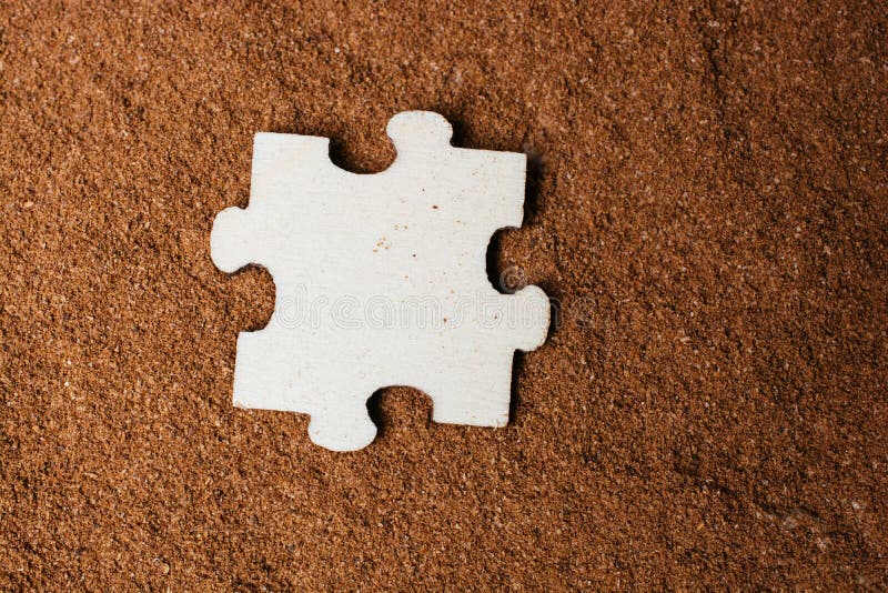 Overhead Shot of a Puzzle Piece on a Brown Surface Under the Lights