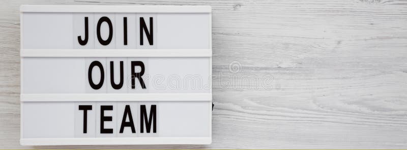 Overhead view, `Join our team` words on a lightbox on a white wooden background. Top view, from above, flat lay. Space for text stock photography