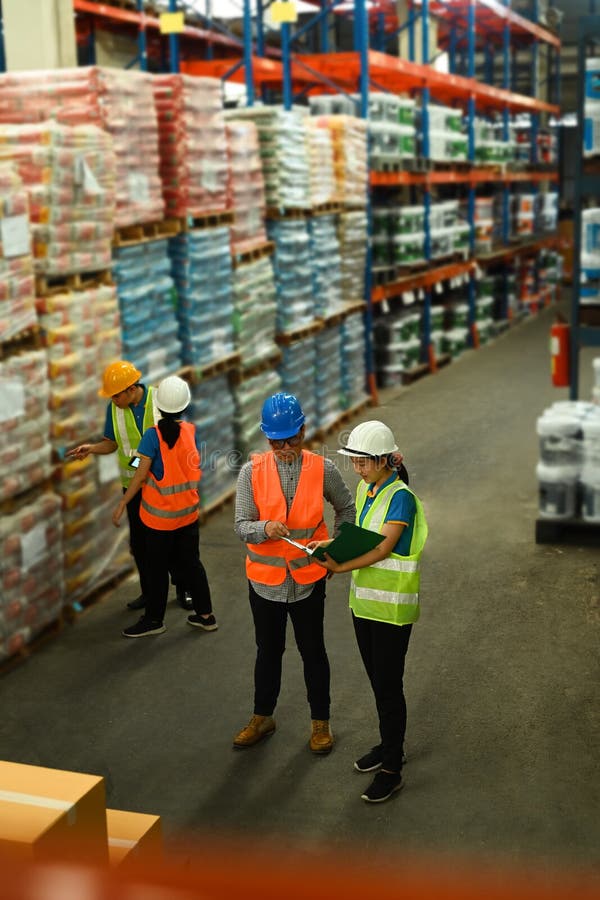 Overhead view of male manager and worker discussing work while walking in aisle between rows of tall shelves full of royalty free stock images