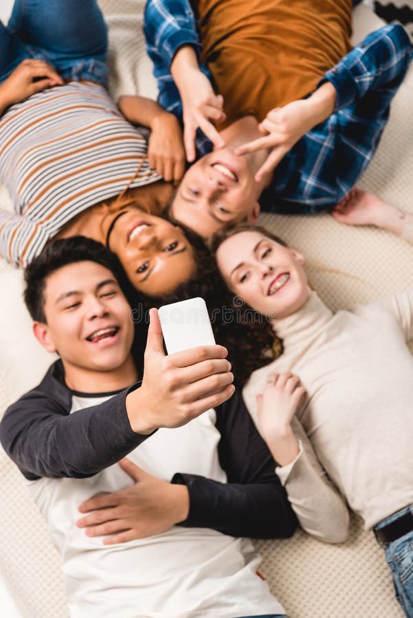 Overhead View Of Multiethnic Teens Taking Selfie While Lying Stock