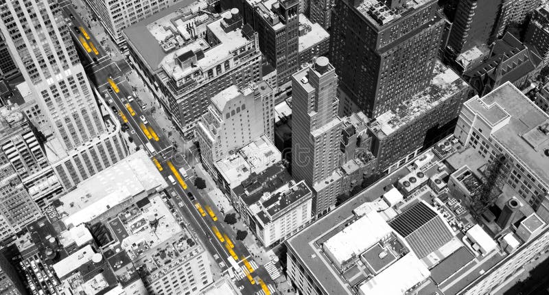 Overhead view of yellow taxis driving through the black and white buildings of Midtown Manhattan in New York City