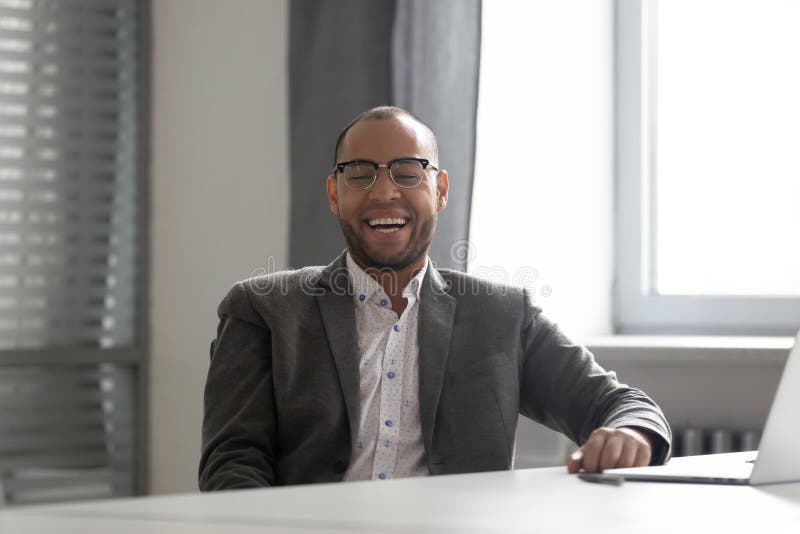 Overjoyed male worker laugh talking with colleague in office