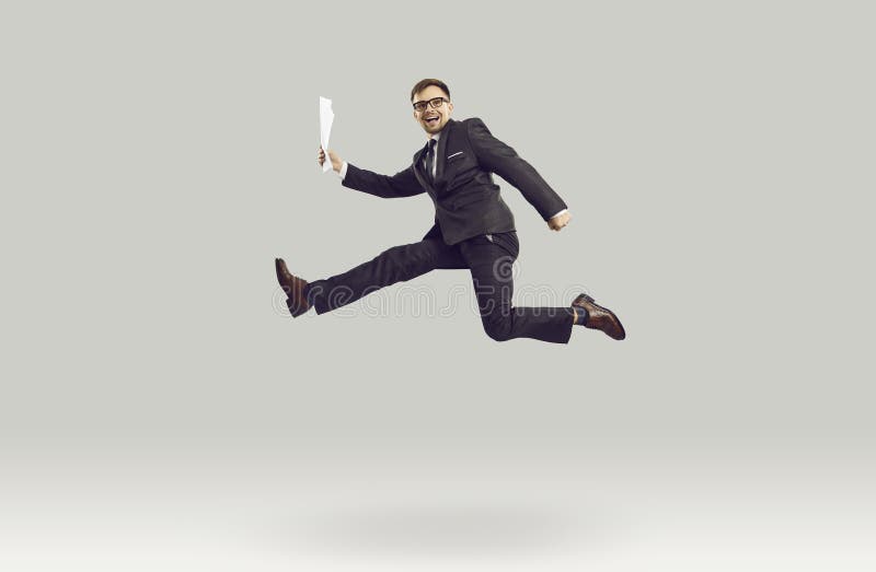 Overjoyed young Caucasian business man in pose of running person smiles at moment of jump royalty free stock photo