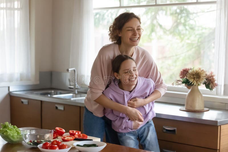 Playful mom and teen daughter have fun cooking together.