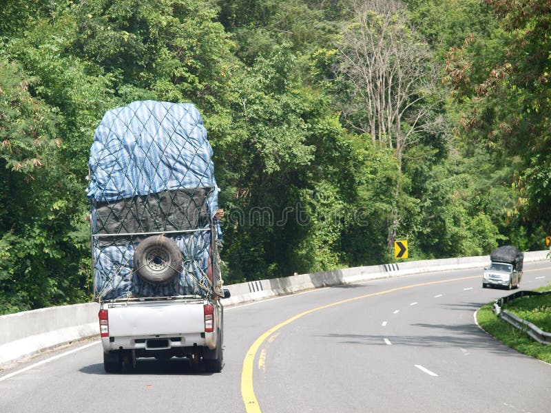 Overloaded mini truck with spare tyre hanging backside on a lonely rural narrow road royalty free stock photos Overloaded mini truck with spare tyre hanging backside on a lonely rural narrow road royalty free stock photos