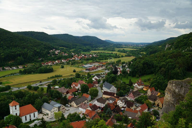 Overlook of the historic township of the climatic health-resort Streitberg from the castle ruins above the town. The karst landscape is characterized by a river, green fields steep and strongly weathered bizarre formations on the hillsides. Luftkurort Streitberg, Franconian Switzerland, Upper Franconia, Bavaria, Germany. 2016. Overlook of the historic township of the climatic health-resort Streitberg from the castle ruins above the town. The karst landscape is characterized by a river, green fields steep and strongly weathered bizarre formations on the hillsides. Luftkurort Streitberg, Franconian Switzerland, Upper Franconia, Bavaria, Germany. 2016