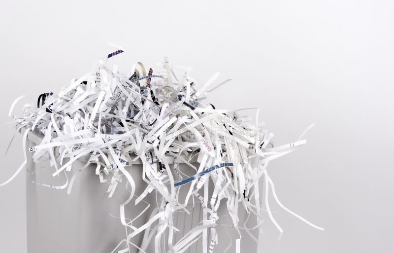 An office shredder overflows with shredded paper. An office shredder overflows with shredded paper.