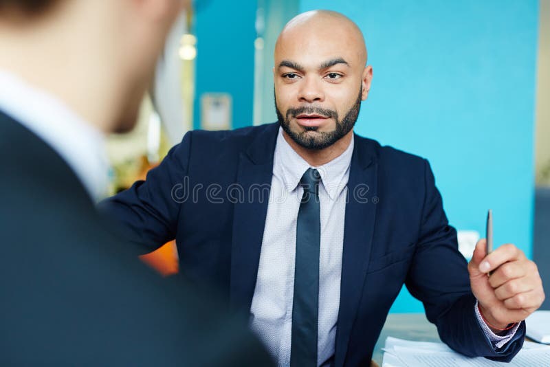 Portrait of charismatic bald businessman talking to partner in meeting, discussing work, looking very confident and successful. Portrait of charismatic bald businessman talking to partner in meeting, discussing work, looking very confident and successful