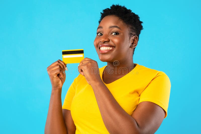 Oversized African Woman Holding Yellow Credit Card, Blue Background. Oversized African Woman Holding Yellow Credit Card Showing It To Camera Advertising Bank royalty free stock images Oversized African Woman Holding Yellow Credit Card, Blue Background. Oversized African Woman Holding Yellow Credit Card Showing It To Camera Advertising Bank royalty free stock images