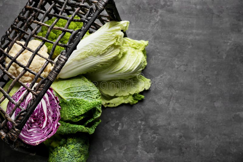 Overturned wicker basket with different kinds of cabbage on grey table stock image