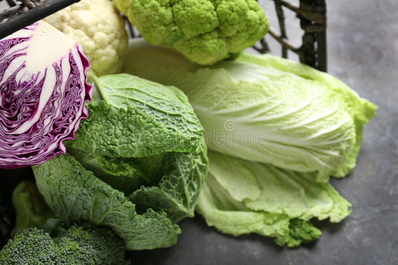Overturned wicker basket with different kinds of cabbage on grey table royalty free stock image