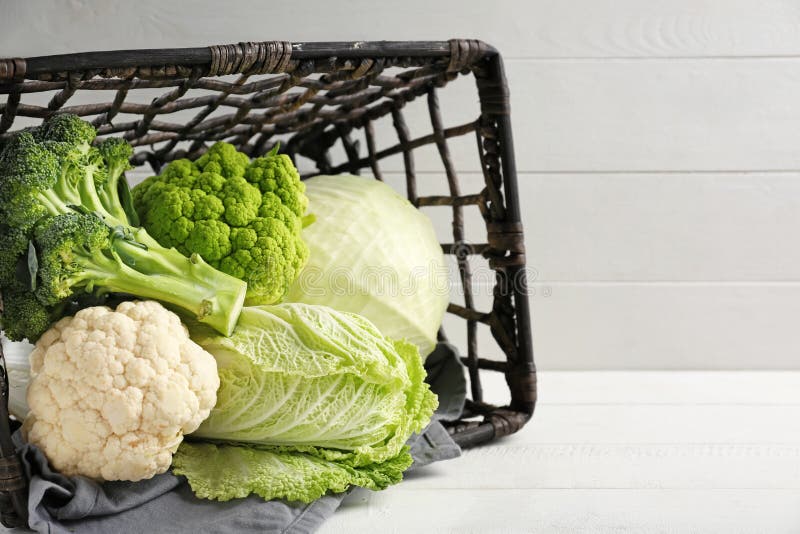 Overturned wicker basket with different kinds of cabbage on white table royalty free stock photo