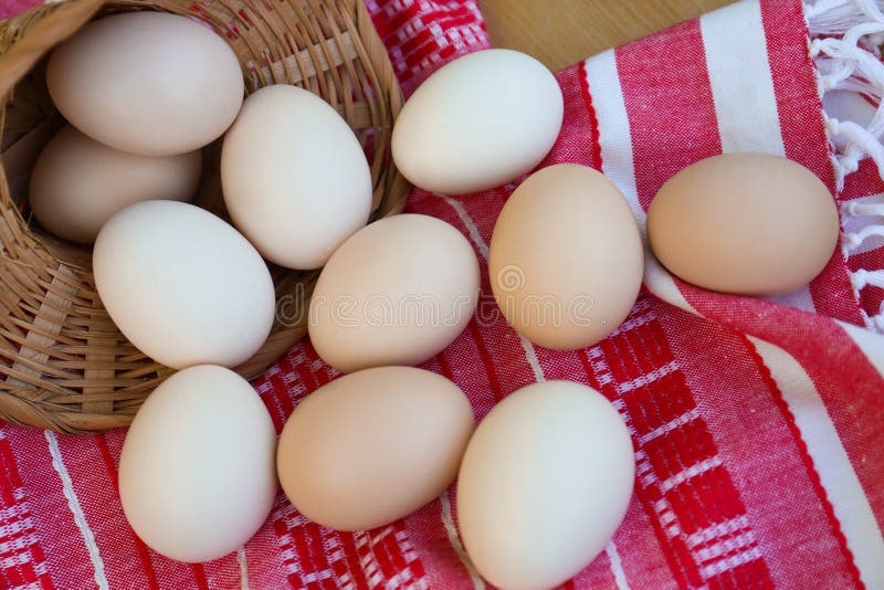 Overturned wicker basket with fresh raw eggs on table stock image