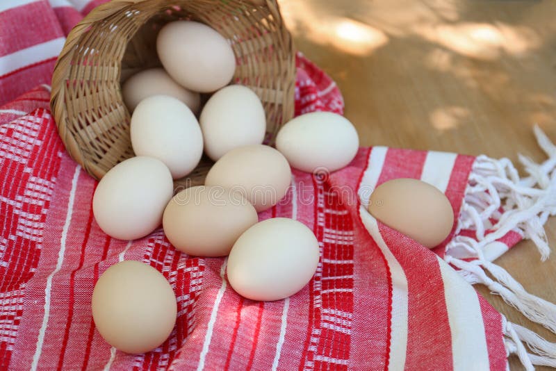 Overturned wicker basket with fresh raw eggs on table royalty free stock photography