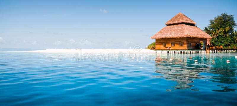 Overwater villas in blue tropical lagoon. Kayaking, clouds.